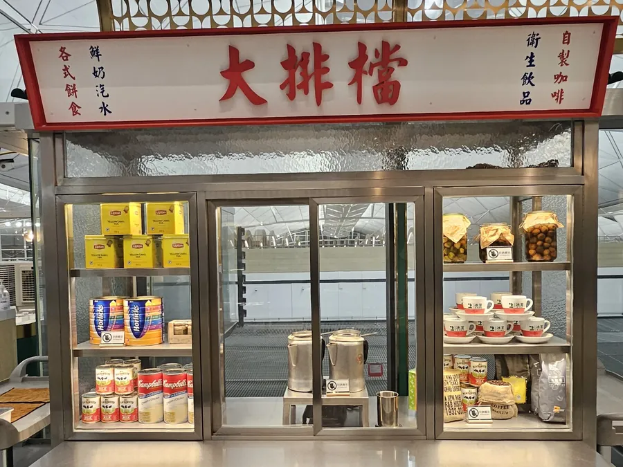 2冰室的大排檔風格展示櫃，掛著紅色「大排檔」招牌；玻璃櫃內，兩個三元牌奶茶壺與茶葉罐、淡奶罐並列。